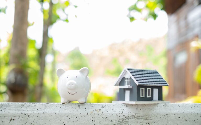 A small house toy and a piggy bank denoting the money that sellers can save once they know how to sell a house by owner