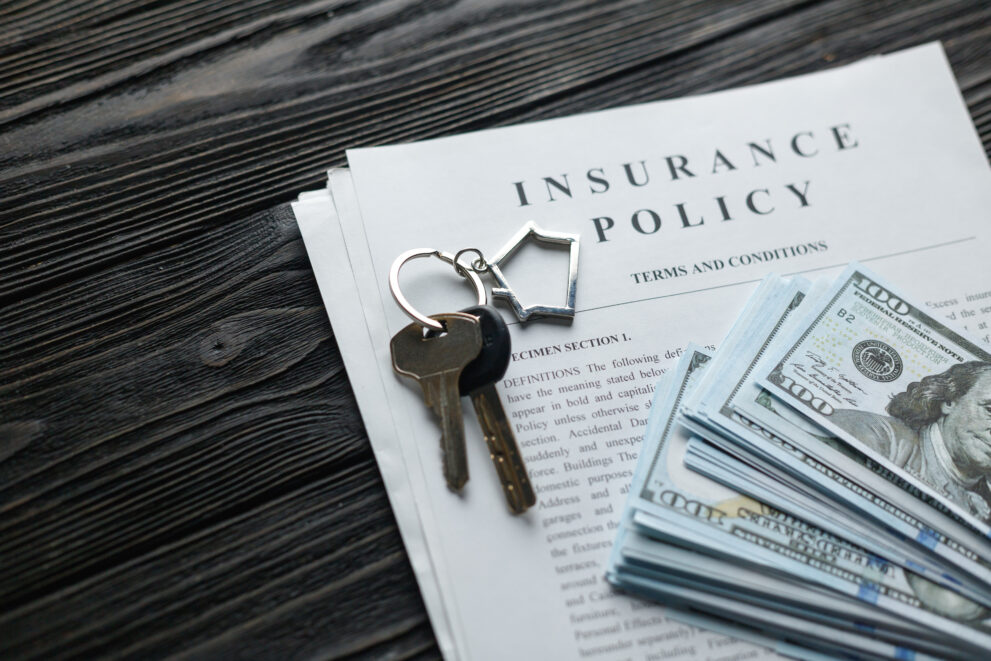 Home insurance policy with keys and dollar money mortgage, loan or home insurance documents.