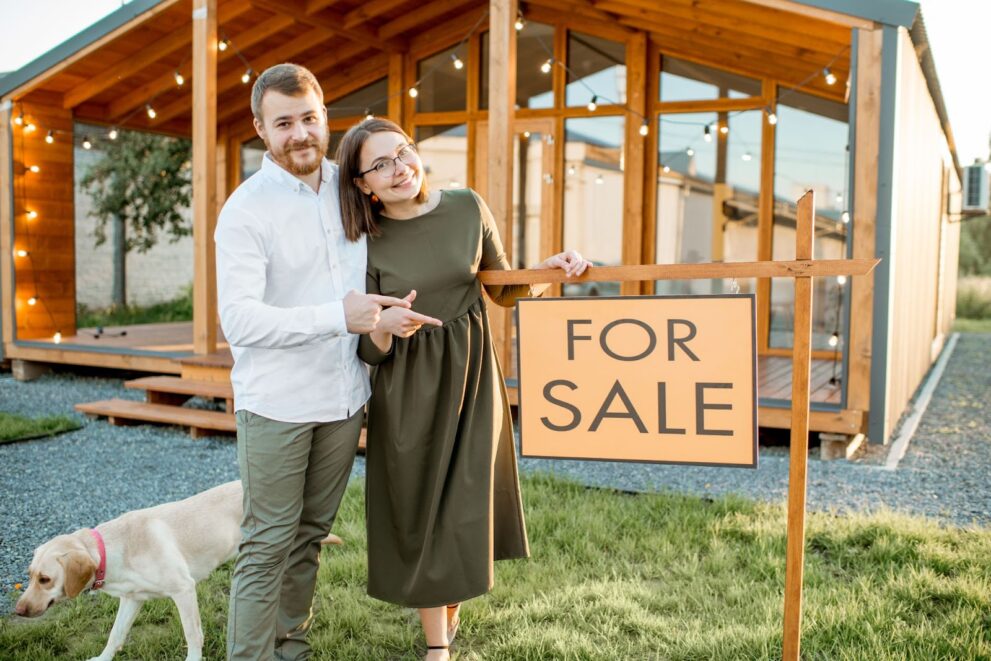 Sellers posing in front of the home for sale sign